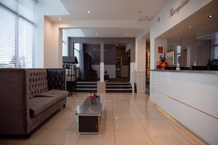 hotel reception in Liverpool with shiny white floors, reception desk and seating area.