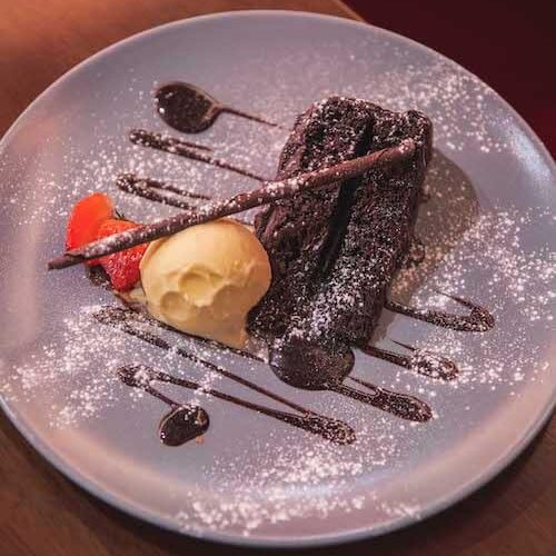 image of chocolate ganache cake and ice cream with chocolate cigarello garnish and strawberry