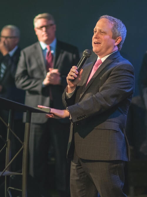 man with microphone speaking at a business meeting lecturn