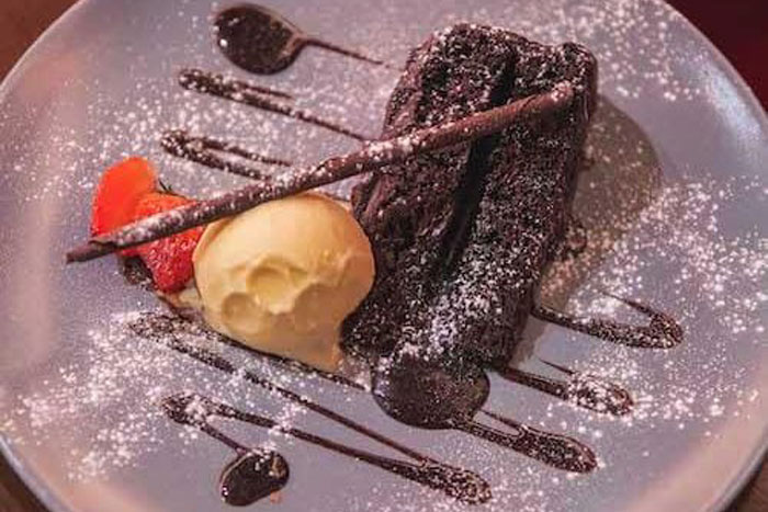 piece of chocolate cake on a plate with ice cream, strawberries at a restaurant in Liverpool