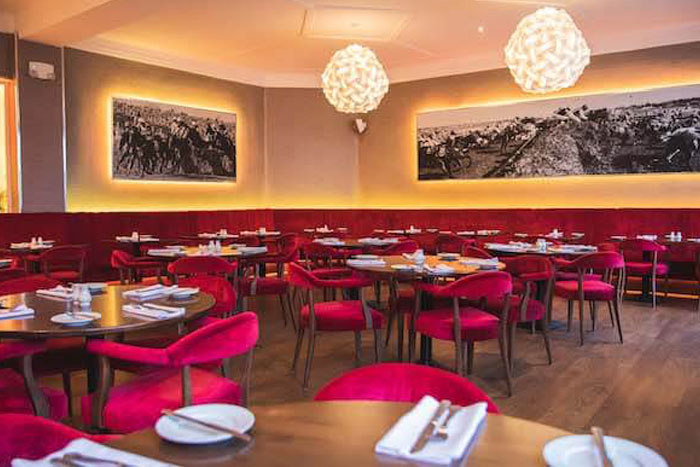 Hotel restaurant with tables set and red chairs. Pictures on the walls of the grand national, Liverpool