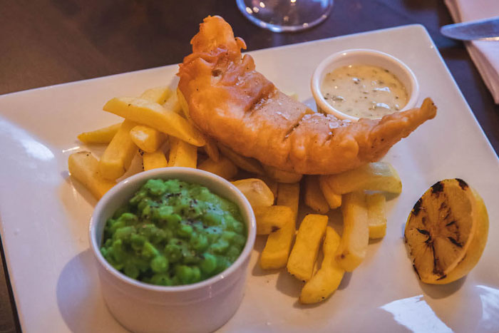 fish and chips and mushy peas on plate at hotel restaurant